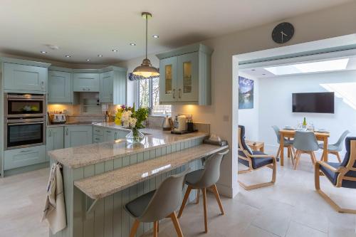 a kitchen with blue cabinets and a dining room at The Grove - Bude Cornwall in Bude