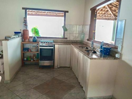 a kitchen with a stove and a sink and a window at Aconchego da Raquel in Itaúnas