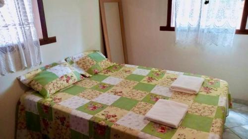 a bed with a quilt and two towels on it at Aconchego da Raquel in Itaúnas