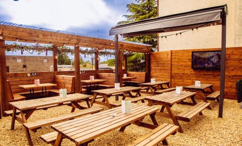 a group of wooden picnic tables in front of a building at The Coachman Hotel in Kilsyth