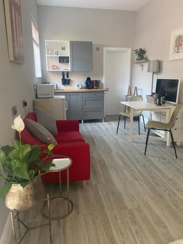 a living room with a red couch and a kitchen at Hugo Mews Bright Studio Apartment in Bray