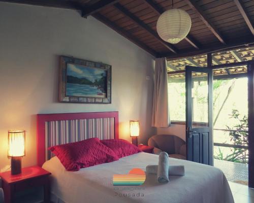 um quarto com uma cama com 2 candeeiros e uma janela em Pousada Aurora na Praia do Rosa