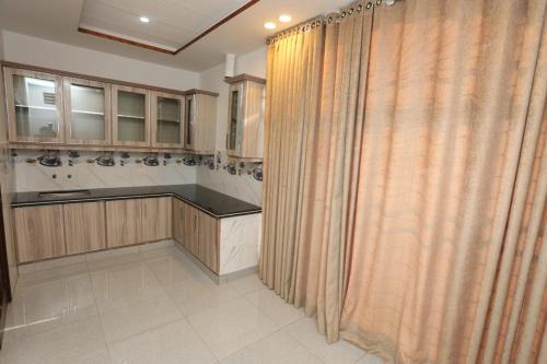 a kitchen with wooden cabinets and a shower curtain at Grand Swiss Hotel&Apartment Lahore in Lahore