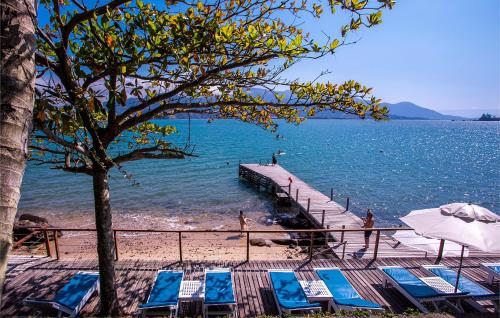 a beach with chairs and an umbrella and a dock at Barra do Piuva Porto Hotel in Ilhabela