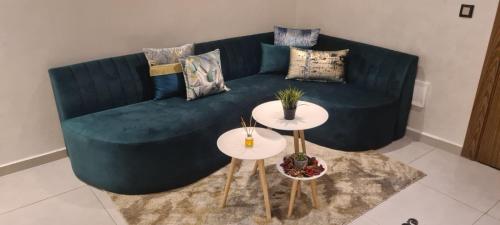 een woonkamer met een blauwe bank en 2 tafels bij Al Anouar Résidence in Kenitra