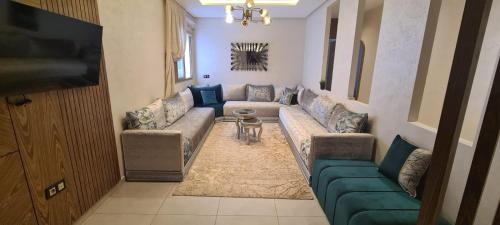 een woonkamer met een bank en een tv bij Al Anouar Résidence in Kenitra