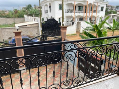 a balcony with a black railing and a house at At Home Lisda in Yaoundé