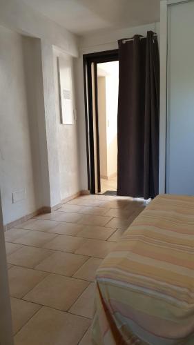 Cette chambre dispose d'un lit et d'une porte menant à un couloir. dans l'établissement Une chambre dans la résidence proche de plage, commerces et centre ville, à Calvi