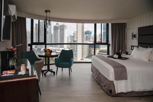Habitación de hotel con cama y mesa con sillas en Plaza Paitilla Inn en Panamá
