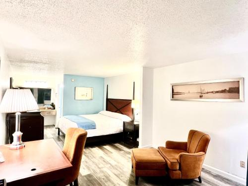 Bayou La BatreにあるBayou Inn & Suitesのベッド、デスク、椅子が備わるホテルルームです。