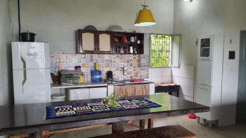 a kitchen with a table and a white refrigerator at Casa Varanda do Tupé in Manaus