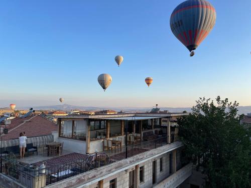 a group of hot air balloons flying over a building at Anatolia Raymonde Cave House in Uçhisar