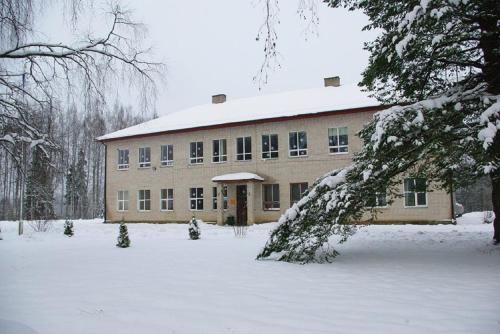 un edificio con nieve en el suelo delante de él en Roosu Talu Accommodation, en Sulbi