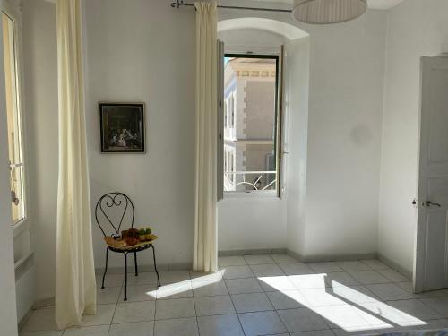 a white hallway with a chair and a window at Casa Eugénie l'appartement de tante Madeleine vue sur les montagnes in Venaco