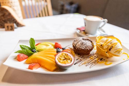 a plate of food with fruit and a cup of coffee at Residence Sägemühle in Prato allo Stelvio
