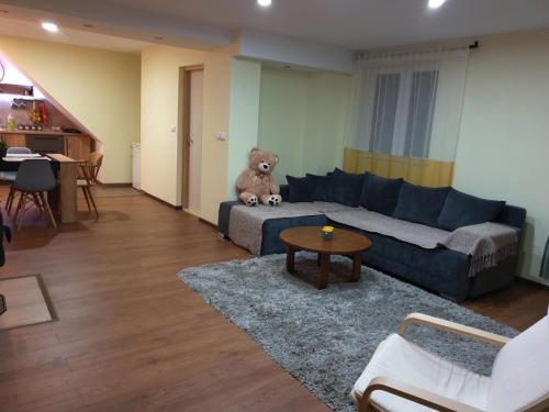 a living room with a teddy bear sitting on a couch at NIKAS Apartman in Donji Milanovac