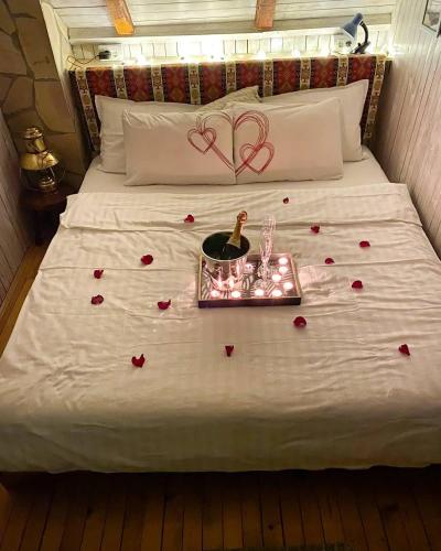 a bed with hearts on it with a tray with a bottle of champagne at Rent a Forest, Cabin Hidden in the Fruška gora in Velika Remeta