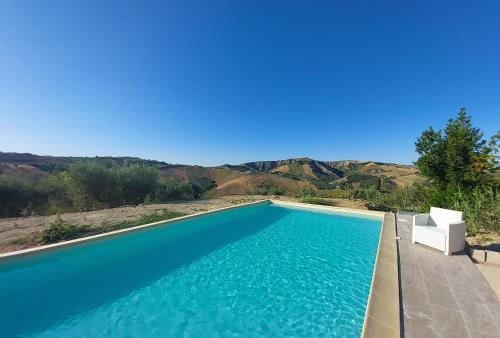 Montefino的住宿－Villa Ferranti Abruzzo，一个带椅子和蓝色海水的游泳池