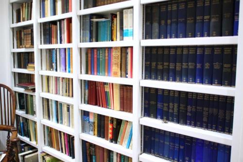 a white book shelf filled with lots of books at Elmham House - Pilgrim Hotel in Little Walsingham