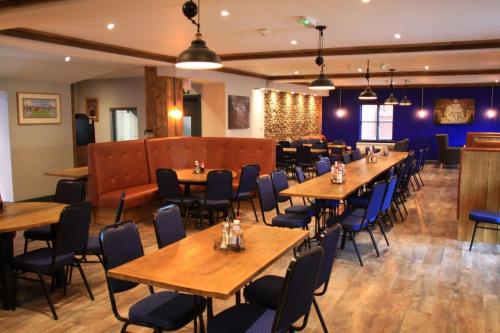 a dining room with wooden tables and chairs at Elmham House - Pilgrim Hotel in Little Walsingham