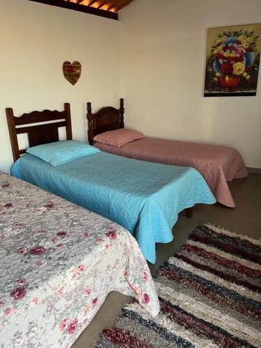 a bedroom with two beds and a rug at Pousada Dona Terezinha in Formiga