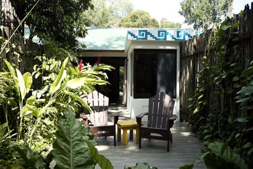 a patio with two chairs and a table in a garden at Hotel Jungle Lodge Tikal in Tikal