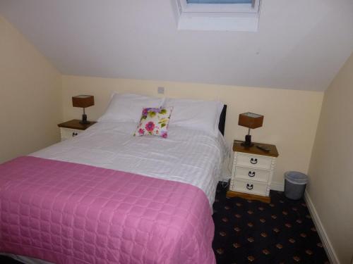 a bedroom with a pink and white bed and two lamps at The Schooner Tavern in Ballycotton