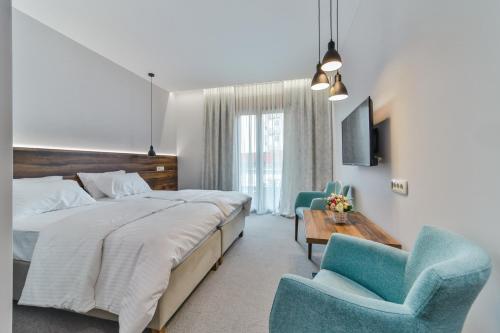 a bedroom with a large bed and two blue chairs at Hotel Vladimir in Budva