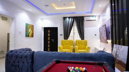 a living room with a pool table and two yellow chairs at Gillant Luxury Homes in Benin City