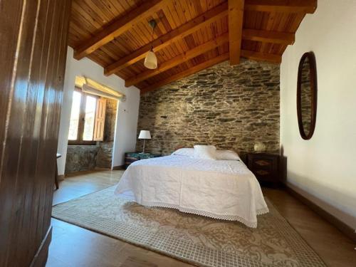 Un dormitorio con una cama y una pared de ladrillo. en Casal de Pedra, en Santa Irene