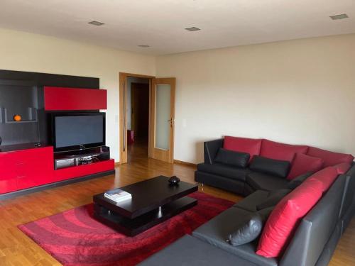a living room with a red couch and a television at PORTO AGUDA BEACH ***** in Arcozelo