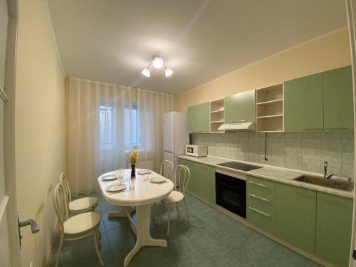 a kitchen with green cabinets and a table and chairs at Апартаменты в центре города in Astana