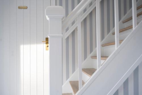 a staircase with white railings and a white stair case at Melsted Badehotel in Gudhjem