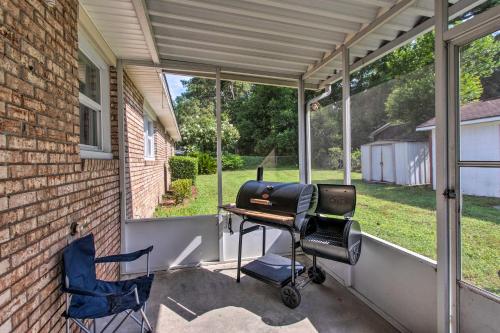 a screened in porch with a grill and two chairs at Cozy Waycross House with Yard and Screened Patio! in Waycross