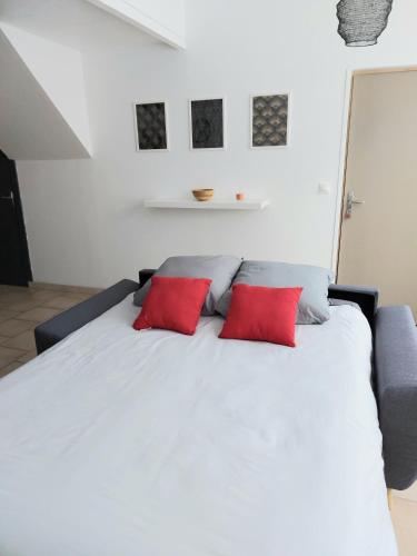 een slaapkamer met een wit bed en 2 rode kussens bij Appart confort#1, centre-ville, Gare à pieds proche commodités calme in Maubeuge