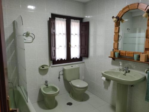 a bathroom with a toilet and a sink and a mirror at Casa Joglar in Beceña