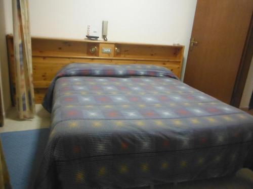 a bed in a bedroom with a wooden headboard at Hotel Mochettaz in Aosta