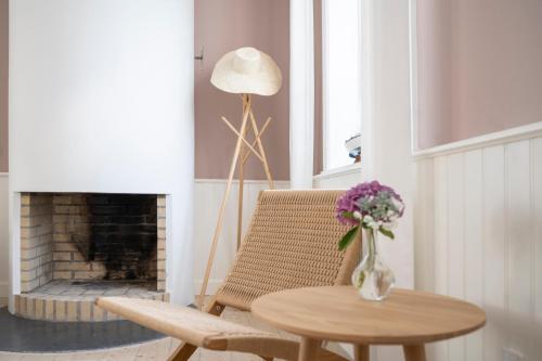 a living room with a table and a chair and a vase of flowers at Melsted Badehotel in Gudhjem