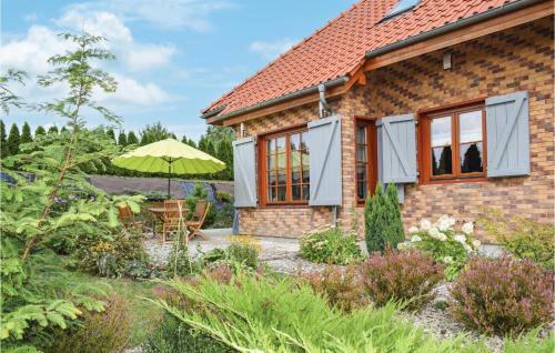 a brick house with a garden and an umbrella at 3 Bedroom Awesome Home In Gardna Wielka in Gardna Wielka