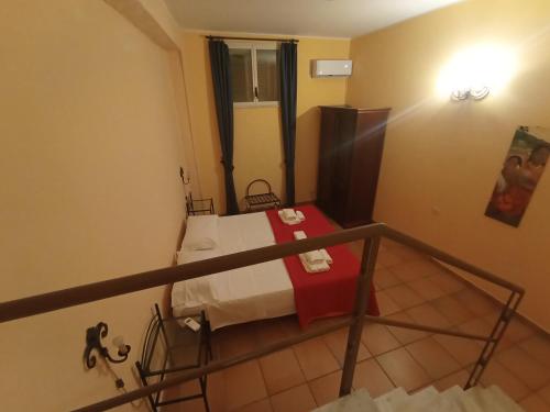 a small room with a bed with a red blanket at Life Hotels Residence dei Baroni in Siracusa