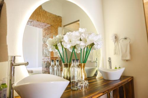 Hotel Tabáa Oaxaca في مدينة أواكساكا: حمام مع حوض وزهور بيضاء على منضدة