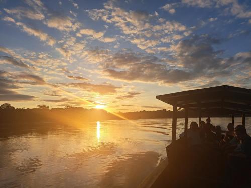 a group of people on a boat on the water at sunset at Andean Wings Sotupa Eco Lodge in Puerto Maldonado