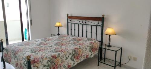 a bedroom with a bed with a floral bedspread and two lamps at Quarteira, Algarve - Seaview - Horizonte Mar in Quarteira