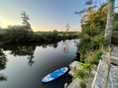 a man is swimming in a river with a boat at Casa do Rio Alva in Arganil