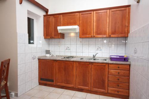 a kitchen with wooden cabinets and a sink at Apartments by the sea Rogoznica - 3094 in Rogoznica