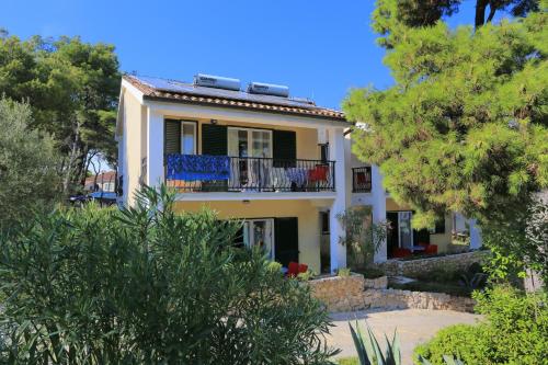 a yellow house with a balcony and trees at Apartments by the sea Rogoznica - 3196 in Rogoznica