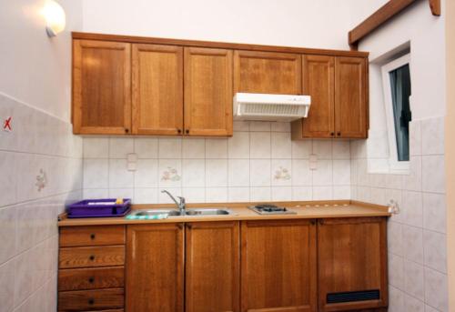 a kitchen with wooden cabinets and a sink at Apartments by the sea Rogoznica - 3196 in Rogoznica