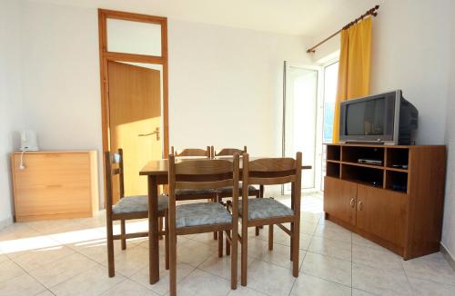 a dining room with a table and chairs and a television at Apartments with a parking space Duce, Omis - 3190 in Duće