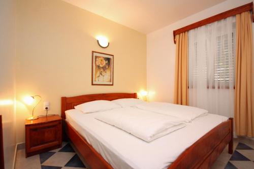 um quarto com uma cama com lençóis brancos e uma janela em Apartments by the sea Rogoznica - 3197 em Rogoznica
