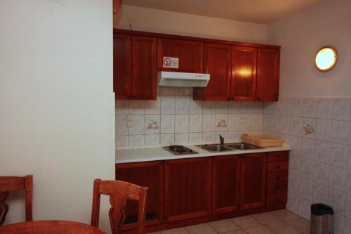 uma cozinha com armários de madeira e um lavatório em Apartments by the sea Rogoznica - 3197 em Rogoznica